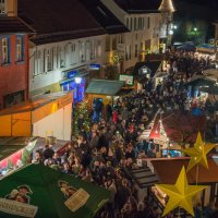 Das Bild zeigt eine Menschenmenge zwischen den Ständen des Muschelfests in der Dunkelheit