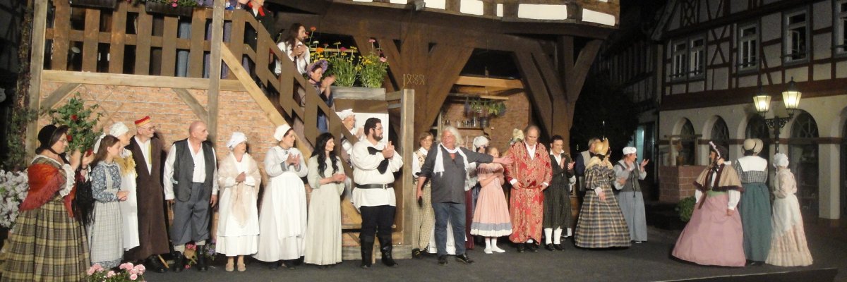 Das Bild zeigt eine Theatergruppe in historischen Kostümen vor dem historischen Rathaus in Michelstadt