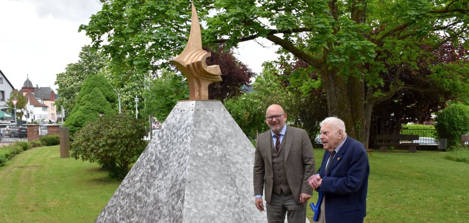 Das Foto zeigt den Künstler Bernd Rosenheim und Landrat Frank Matiaske vor der Skulptur "Pyramide des Perseus" im Hof das Landratsamts.