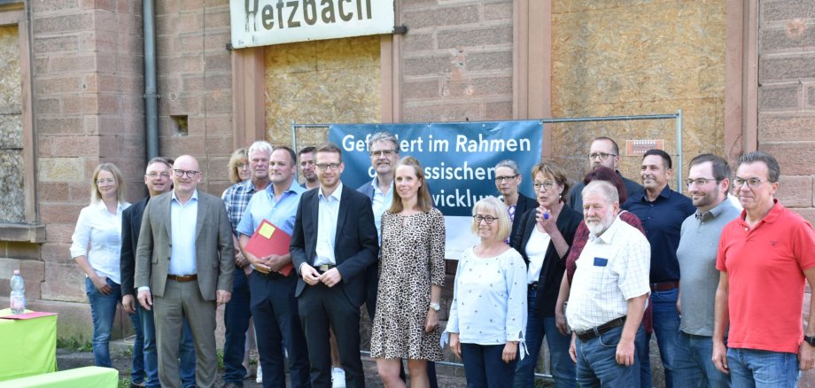 Das Foto zeigt eine Gruppe von Menschen vor dem Bahnhofsgebäudei in Hetzbach mit Staatssekretär Ruhl, Landrat Matiaske und Bürgermeister Kehrer.