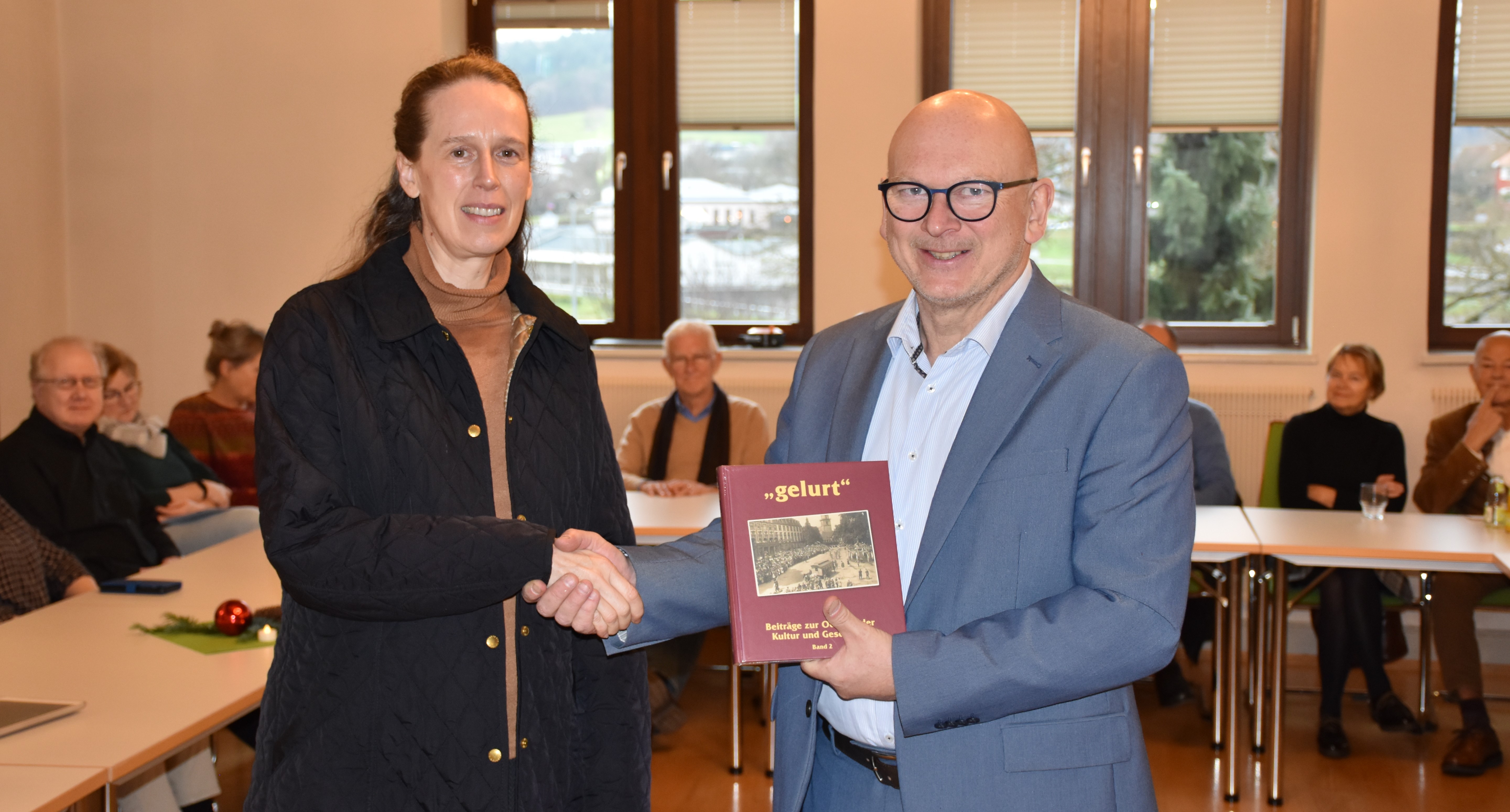 DAs Foto zeigt, wie Landrat Matiaske der Lektorin Schmidt-Herrmann ein neues "gelurt" überreicht.