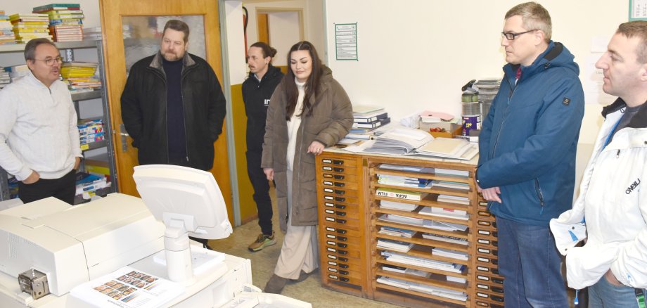Das Foto zeigt Mitarbeiterinnen und Mitarbeiter des Kommunalen Job-Centers beim Besuch der Druckerei Müller in Erbach.