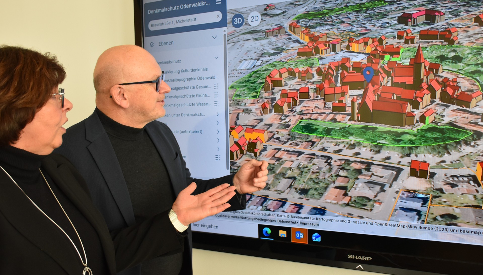 Landrat Frank Matiaske und Jutta Stegmüller von der Bauverwaltung des Odenwaldkreises schauen sich eine 3D-Ansicht von Michelstadt an.