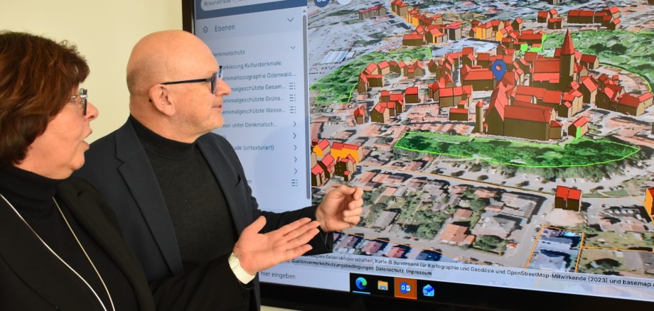 Landrat Frank Matiaske und Jutta Stegmüller von der Bauverwaltung des Odenwaldkreises schauen sich eine 3D-Ansicht von Michelstadt an.