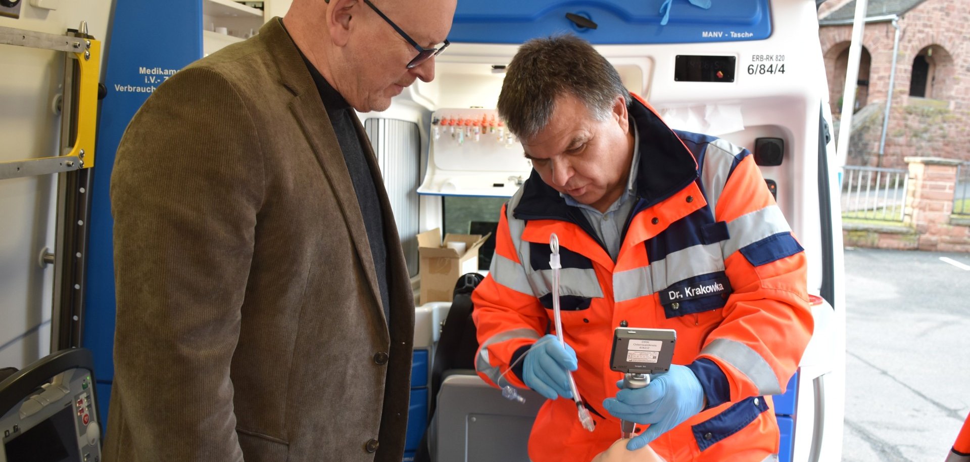 Das Foto zeigt Landrat Matiaske und den ÄLRD Dr. Krakowka in einem Rettungswagen bei einer Larnygoskopie an einer Übungspuppe.