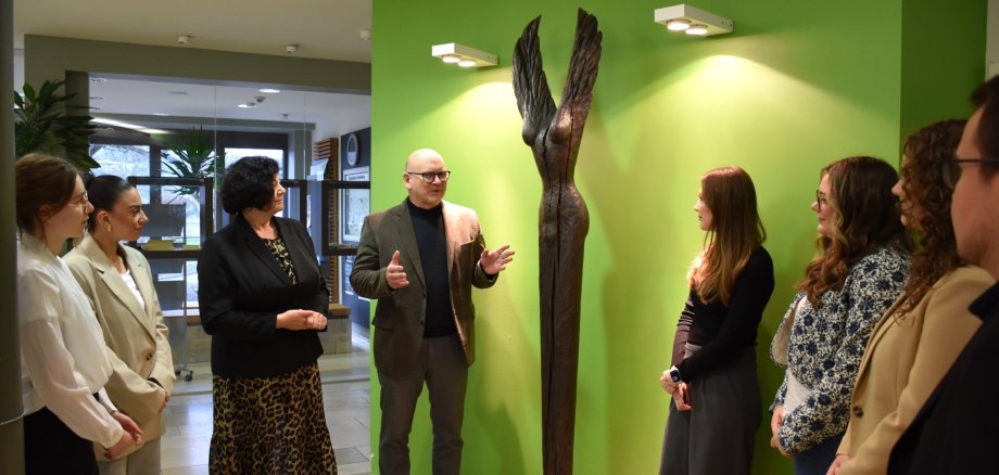 Landrat Matiaske erläutert Auszubildenden die Wächter-Figur im Foyer des Landratsamts.