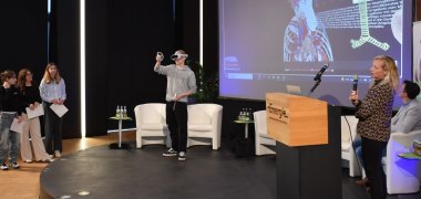 Das Foto zeigt einen Schüler des Beruflichen Schulzentrums Odenwaldkreis, der beim Odenwald-Dialog im Haus der Energie/Volksbank-Atrium in Erbach den Einsatz einer VR-Brille demonstriert.
