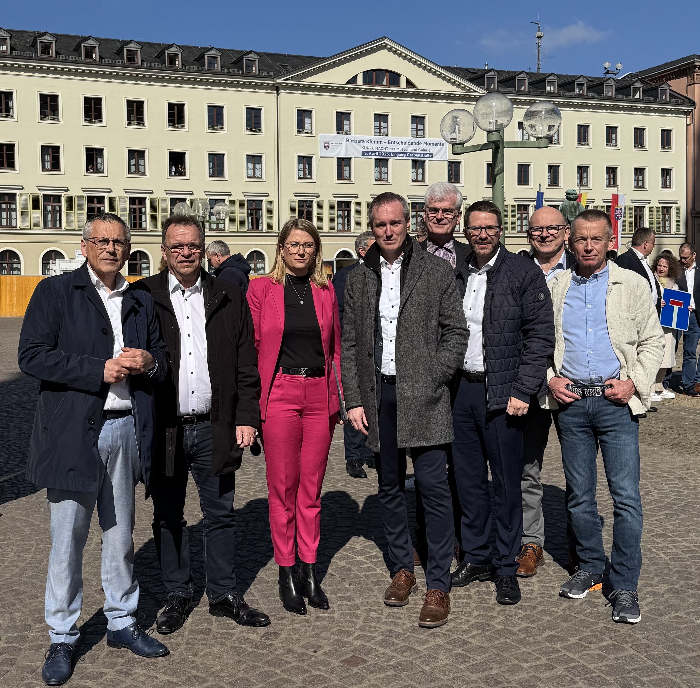 Das Foto zeigt eine Landrätin und sieben Landräte aus Nord- und Südhessen am Rand einer Demonstratoin in Wiesbaden.