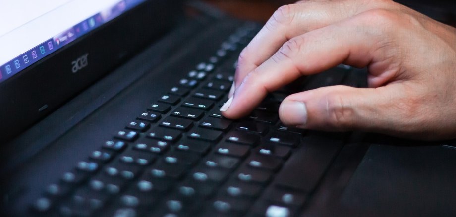 Das Foto zeigt eine Hand, die auf einer Computertastatur liegt.