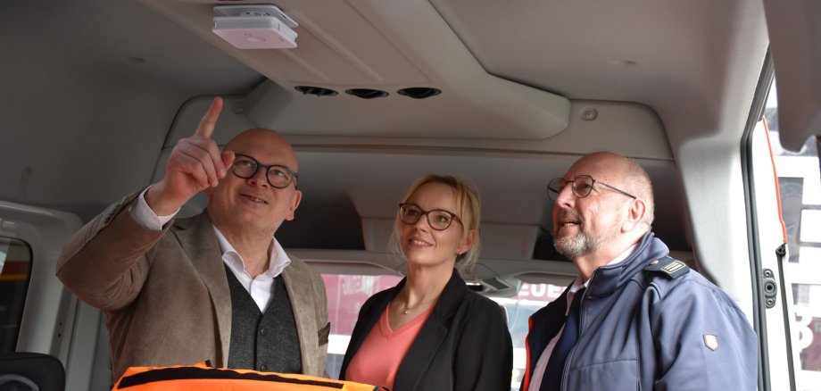 Landrat Matiaske, Projektleiterin Helfrich und Kreisbrandinspektor Friedrich in einem Mannschaftswagen der Feuerwehr Erbach, in dem ein neuer Rauchmelder installiert wurde