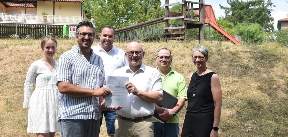 Das Foto zeigt Landrat Matiaske und Bürgermeister Horlacher mit Mitarbeitenden bei der Bescheidübergabe auf dem Spielplatz.