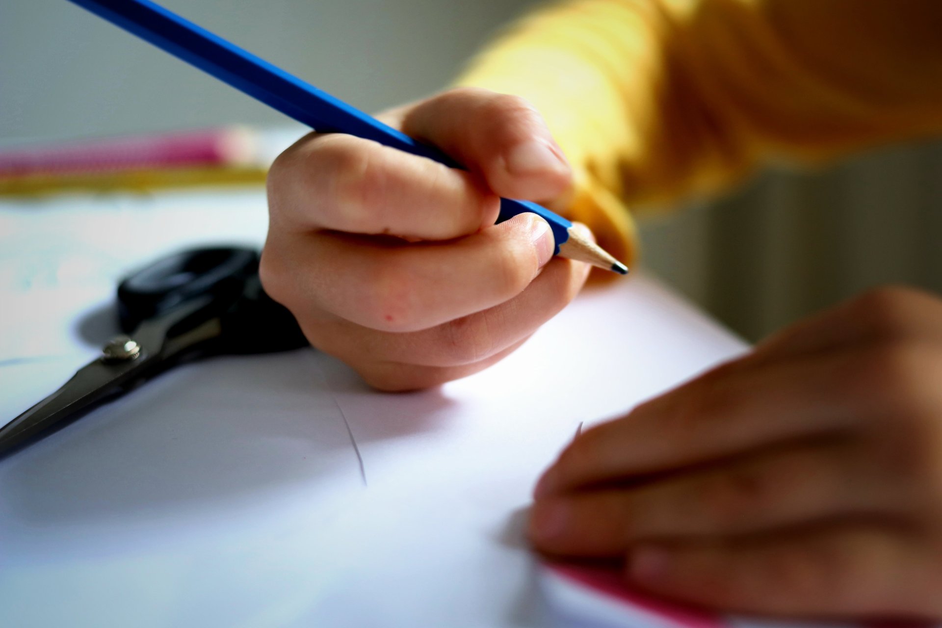 Das Foto zeigt ein Schulkind, das einen Stift in der Hand hält.