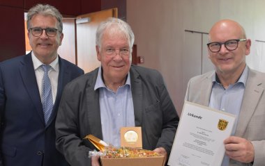 Das Foto zeigt Dr. Michael Reuter mit der Ehrenplakette in Gold, übereicht von Landrat Frank Matiaske (rechts) und Kreistagsvorsitzendem Rüdiger Holschuh (links)