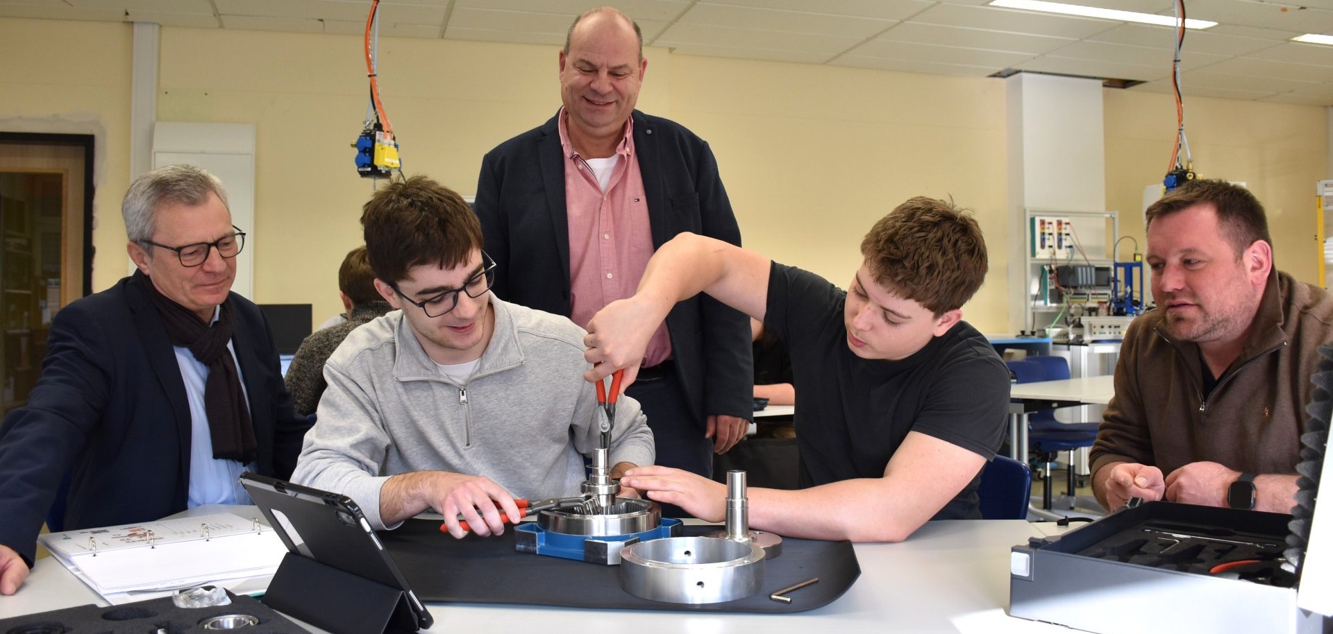 Zwei Schüler des BSO bauen ein Getriebe zusammen. Ihnen schauen zu: Bildungsdezernent Oliver Grobeis, Schulleiter Horst Schad und Lehrer Sebastian Gebhardt.