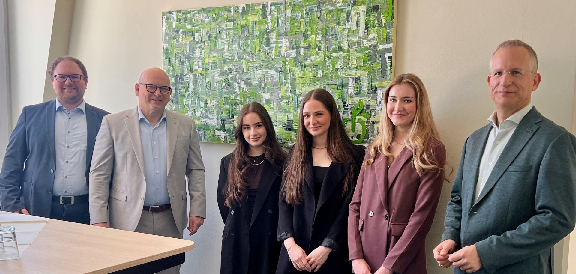Das Foto zeigt drei Schülerinnen der EGS mit ihrem Kunst-Lehrer, dem Landrat und dem Leiter der Schulverwaltung vor dem Gemälde.